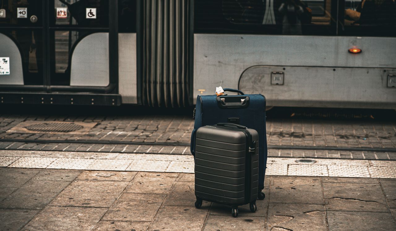Two suitcases on street beside a tram in Florence, Italy, highlighting travel theme.